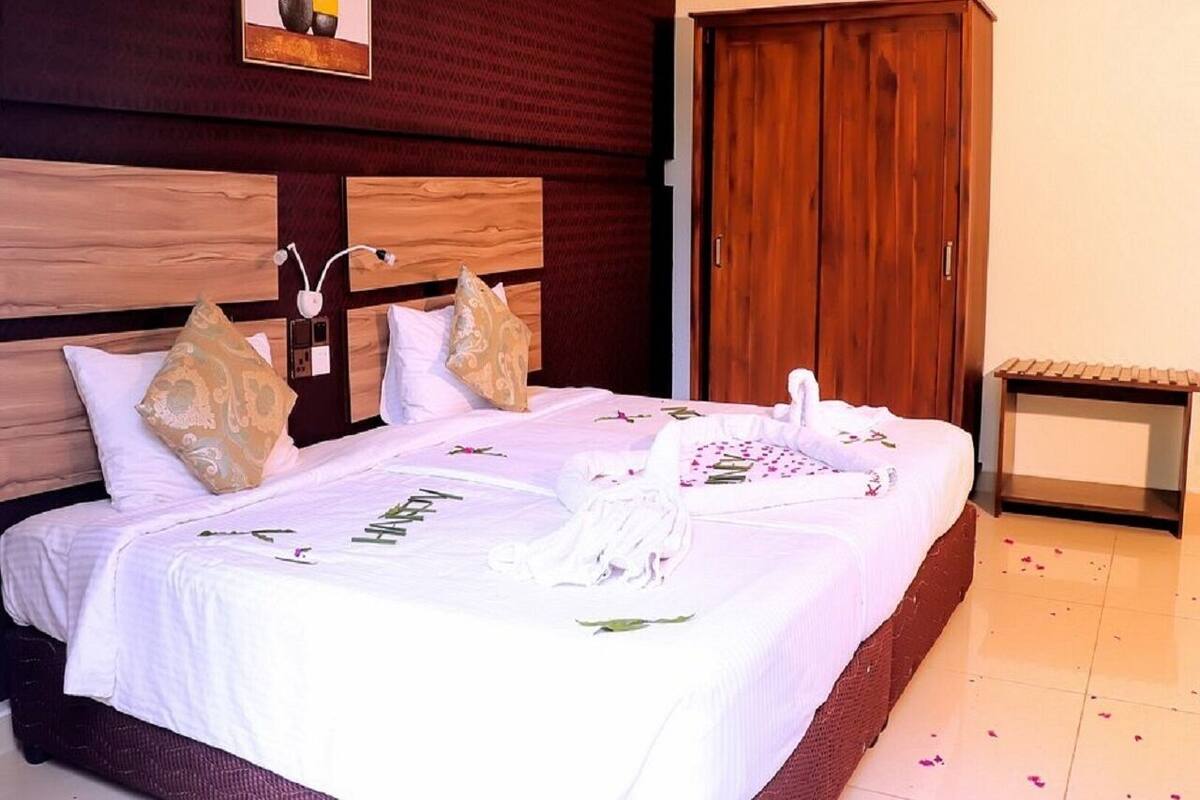 A neatly made bed with white linens, a wooden headboard, and decorative pillows.