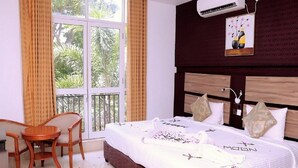A hotel room with a bed, a desk, and a window with curtains.