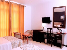Habitación de hotel con dos camas, un escritorio, una silla, un televisor y un espejo.