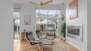 Uma sala de estar moderna com teto de vidro, lareira e área de jantar com vista para o exterior.