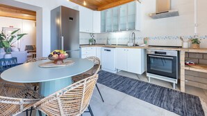 A modern kitchen with white cabinets, a stainless steel refrigerator, and a built-in oven.