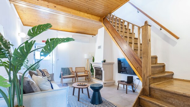 A living room with a sofa, chairs, a coffee table, a fireplace, and a staircase.