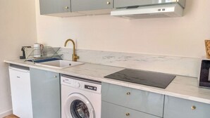 Eine kleine Küche mit Waschmaschine, Spüle und Mikrowelle.