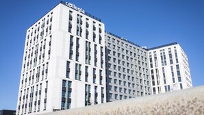 Ein mehrstöckiges Gebäude mit einem gut sichtbaren 'collegia'-Schild oben, das ein modernes architektonisches Design mit einer Anordnung von Fenstern und Balkonen aufweist.