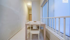 A narrow corridor with a dining table and chairs, a window with blinds, and a door at the end. - A Modern 2BR Sliema APT Near Ferry | W/AC & WIFI (Sliema)