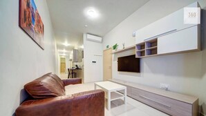 A modern living room with a brown leather sofa, a white coffee table, a TV mounted on a wall, and a minimalist cabinet. - A Modern 2BR Sliema APT Near Ferry | W/AC & WIFI (Sliema)