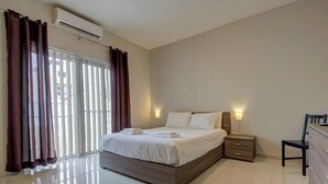 A bedroom with a large bed, a nightstand, a chair, and a dresser. - A Modern 2BR Sliema APT Near Ferry | W/AC & WIFI (Sliema)