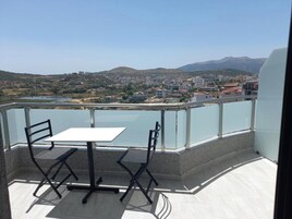Un balcon avec une table et des chaises, donnant sur une ville et une étendue d’eau.