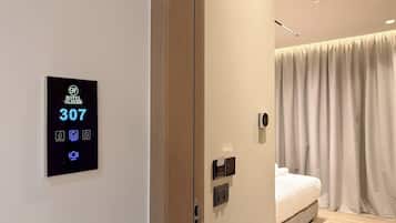 Una habitación de hotel moderna con una llave electrónica, una cama, una mesita de noche y una cortina.