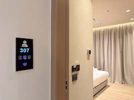 A modern hotel room with a digital keycard, a bed, a bedside table, and a curtain.