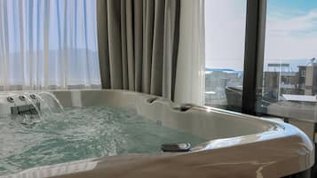 A hot tub with water jets, a window with a view of buildings, and a curtain.