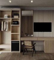 Un salon moderne doté d’un téléviseur encastré, d’étagères en bois, d’une petite armoire noire et d’un fauteuil en osier.