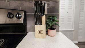 A kitchen with a stove, a knife block, and a potted plant. - Quiet & Relaxing 2BR - King Bed/Pool/Gym Near UAB/Hospitals (Homewood)