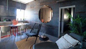Ein modernes Wohnzimmer mit Essbereich, einem runden Spiegel und einer großen Pflanze.