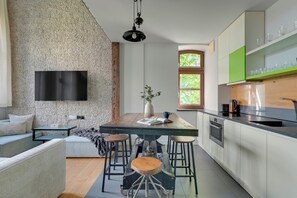 A modern kitchen with a stone wall, a flat-screen TV, and a dining area with stools. - Sopot Loft Living z Parkingiem (Sopot)