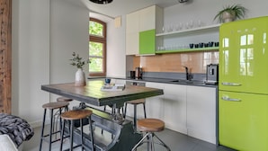 Eine moderne Küche mit Kochinsel, Barhocker, einem grünen Kühlschrank und einem Fenster für natürliches Licht.