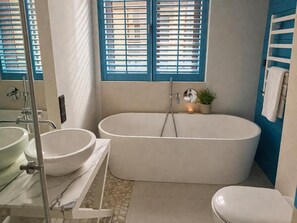 Ein Badezimmer mit einer freistehenden Badewanne, einem weißen Waschbecken und einer Toilette.