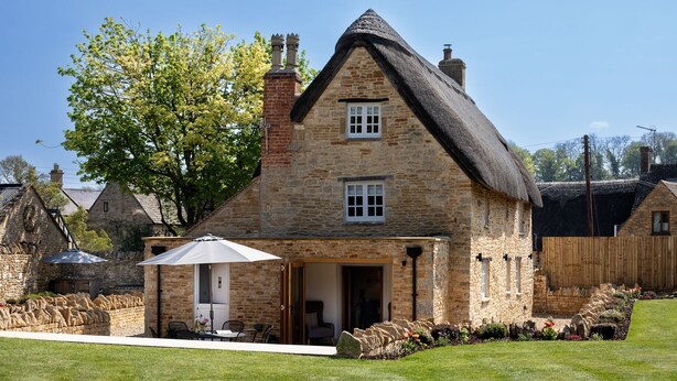 Une maison en pierre avec un toit de chaume, une porte et une petite fenêtre.