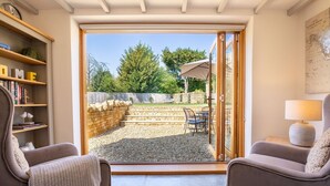 Une pièce dotée d’une porte-fenêtre coulissante donnant sur un patio agrémenté d’un mur en pierre, de mobilier d’extérieur et d’une carte affichée sur le mur.