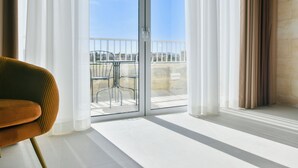 Een kamer met een grote schuifdeur die uitkomt op een balkon met een metalen reling.