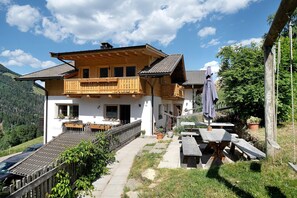 Ein zweistöckiges Holzhaus mit Balkon, einem Kiesweg und Sitzgelegenheiten im Freien.