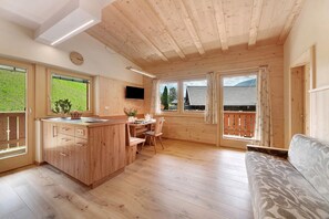 A wooden cabin interior with a kitchen, dining area, and a sofa. - Apartment 'Marschalkhof Peilstein' with Mountain View, Shared Garden and Wi-Fi (San Pancrazio)