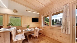A wooden interior with a dining area, a TV mounted on the wall, and large windows. - Apartment 'Marschalkhof Peilstein' with Mountain View, Shared Garden and Wi-Fi (San Pancrazio)