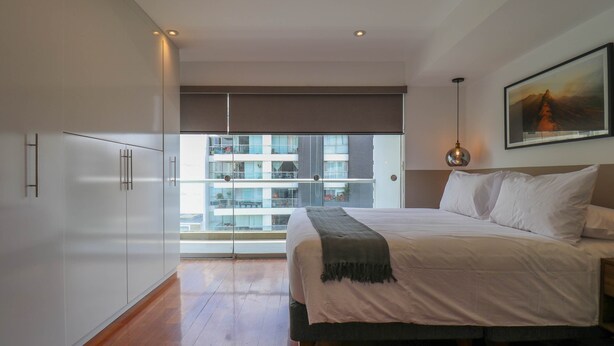 Een slaapkamer met een groot bed, een balkon met uitzicht en een schilderij aan de muur.