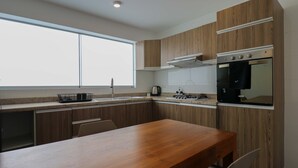 Een moderne keuken met houten kastjes, een roestvrijstalen oven en een groot raam.