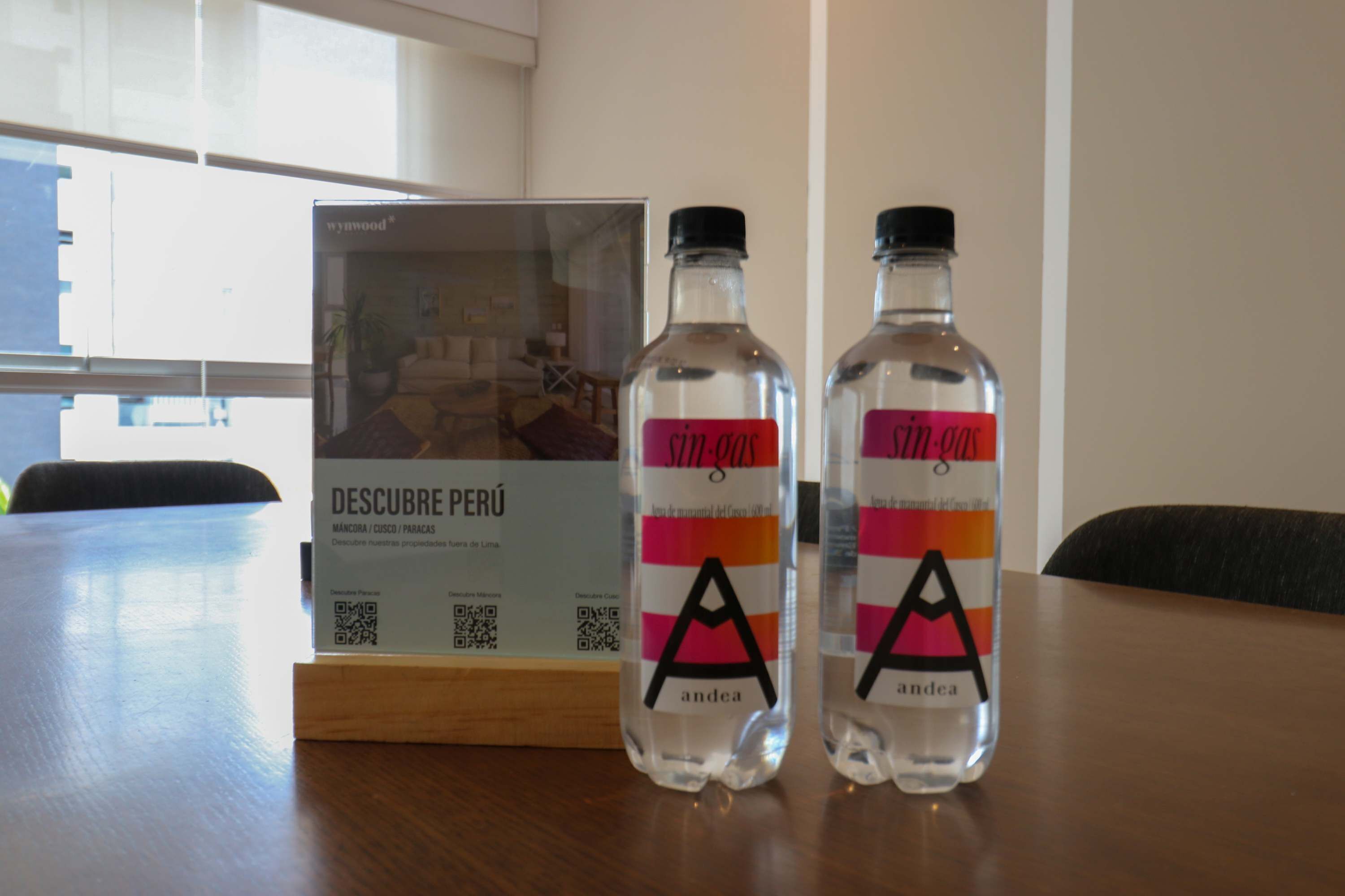 Two bottles of 'SITGES' water on a table with a 'DESCUBRE PERÚ' sign in the background.