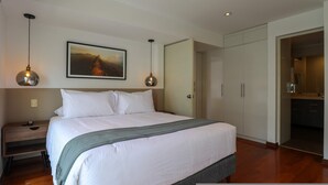 Een slaapkamer met een groot bed, nachtkastje, schilderij en een kledingkast.