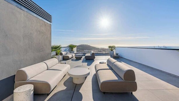 Une terrasse sur le toit avec des sièges extérieurs, une vue sur la mer et une montagne qui se profile à l’horizon.