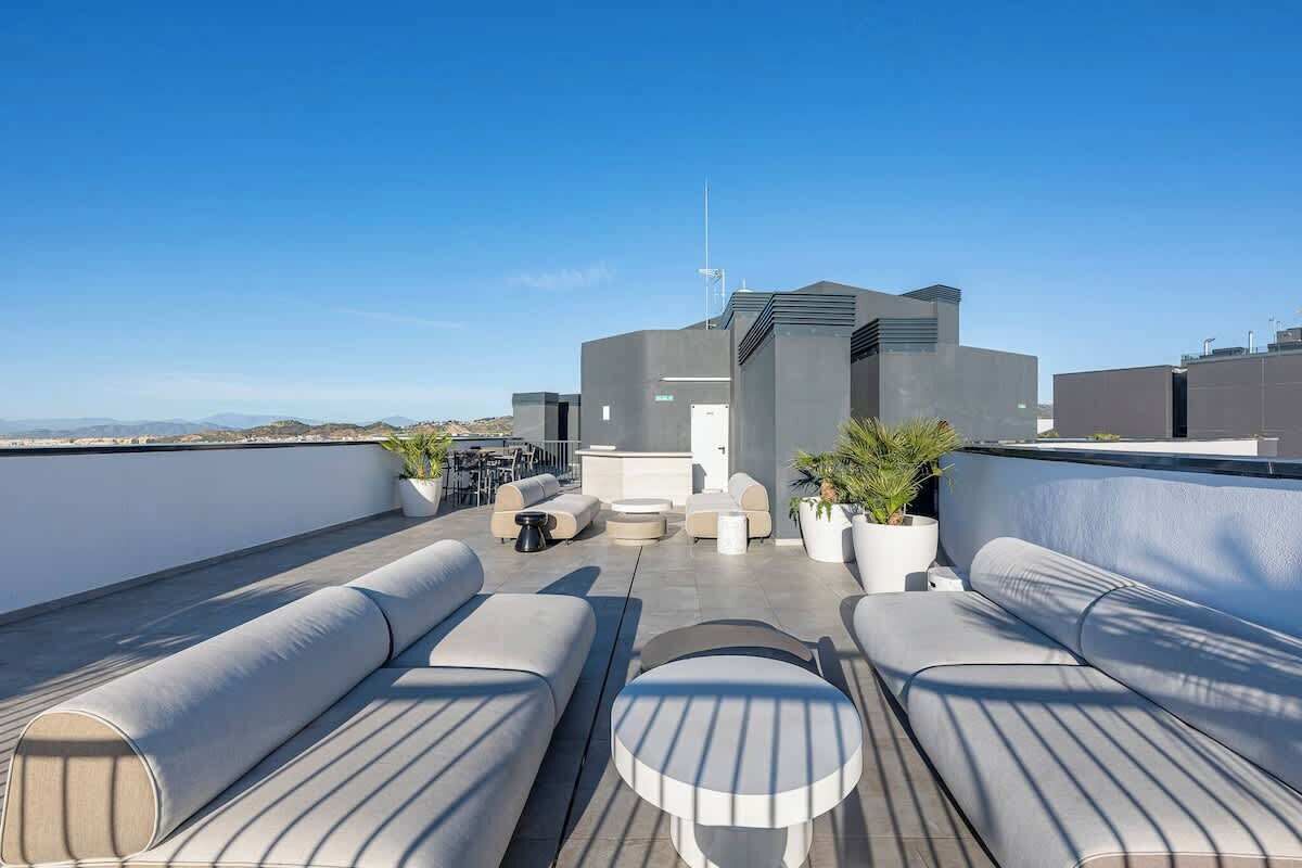 Una terraza en la azotea con asientos modernos, una pequeña mesa y plantas en macetas.