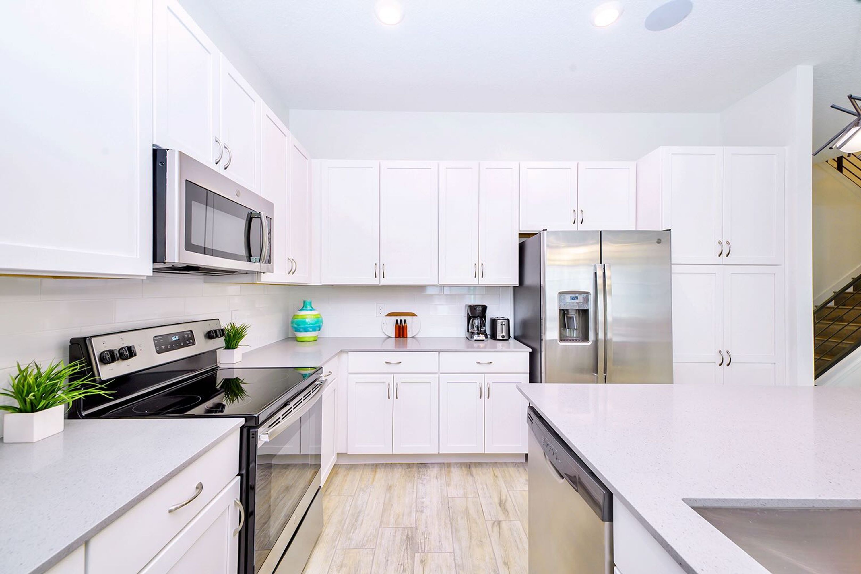 A modern kitchen with white cabinets, stainless steel appliances, and a tiled backsplash.