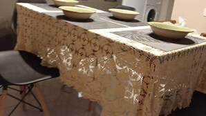 Un tavolo da pranzo con tovaglia in pizzo, sedie e ciotole sopra.