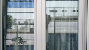 Una finestra con tenda decorata e vista su un edificio con diversi piani e balconi.