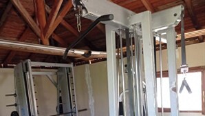 Una palestra con attrezzatura per sollevamento pesi, panche e pavimento verde.