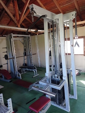 Ein Fitnessstudio mit Krafttrainingsgeräten, Bänken und einem grünen Boden.