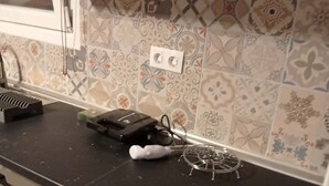 Una cucina con piastrelle decorate, un piano di lavoro nero e un forno a microonde.