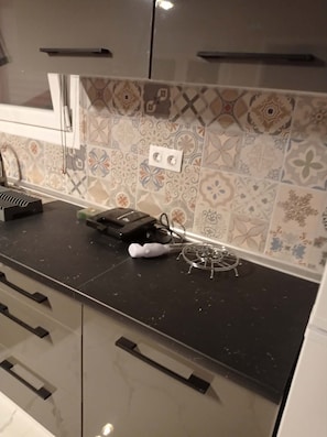 Eine Küche mit gemusterten Fliesen, einer schwarzen Arbeitsplatte und einer Mikrowelle.