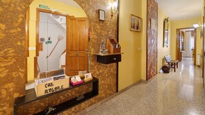 Un hall d’accueil d’hôtel avec un mur en marbre, un comptoir d’accueil en bois, un miroir et un banc dans le couloir.