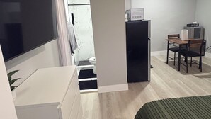 Une chambre comprenant un lit, un bureau avec une chaise, une petite kitchenette et une salle de bain.