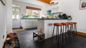 Una cocina moderna con armarios blancos, encimera negra y una zona con taburetes de bar.
