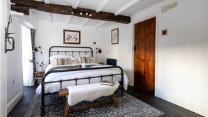 Een slaapkamer met een bed, een bankje en een kamerkleed met een patroon.