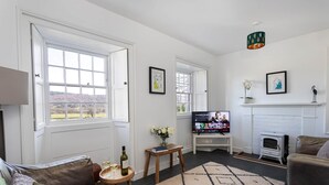 Una sala de estar con chimenea, televisor, sofá y ventana con vistas al exterior.