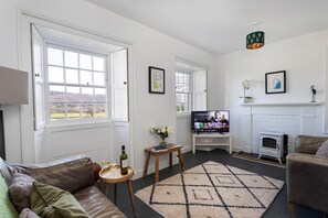 Un salon avec une cheminée, un téléviseur, un canapé et une fenêtre donnant sur l’extérieur.