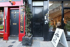A storefront with a black door, a red and black facade, and a signboard. - Perfect Booking Deptford High Street 3 Bed Flat (London)