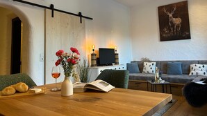 En moderne stue med et træspisebord, en sofa, et fjernsyn og et billede af et rådyr.