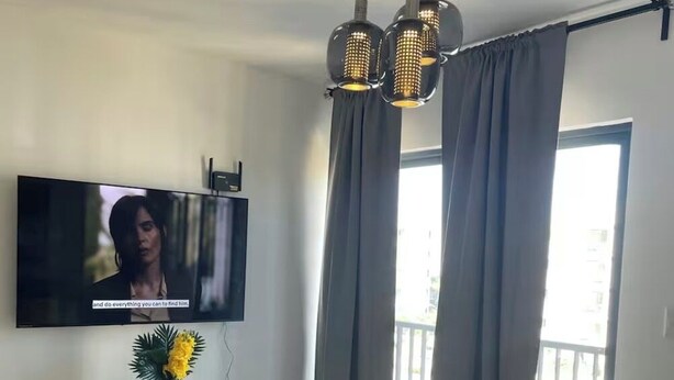 Ein modernes Wohnzimmer mit Flachbildfernseher, weißem Konsolentisch, Couchtisch und Sofa.