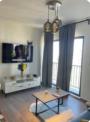 Ein modernes Wohnzimmer mit Flachbildfernseher, weißem Konsolentisch, Couchtisch und Sofa.
